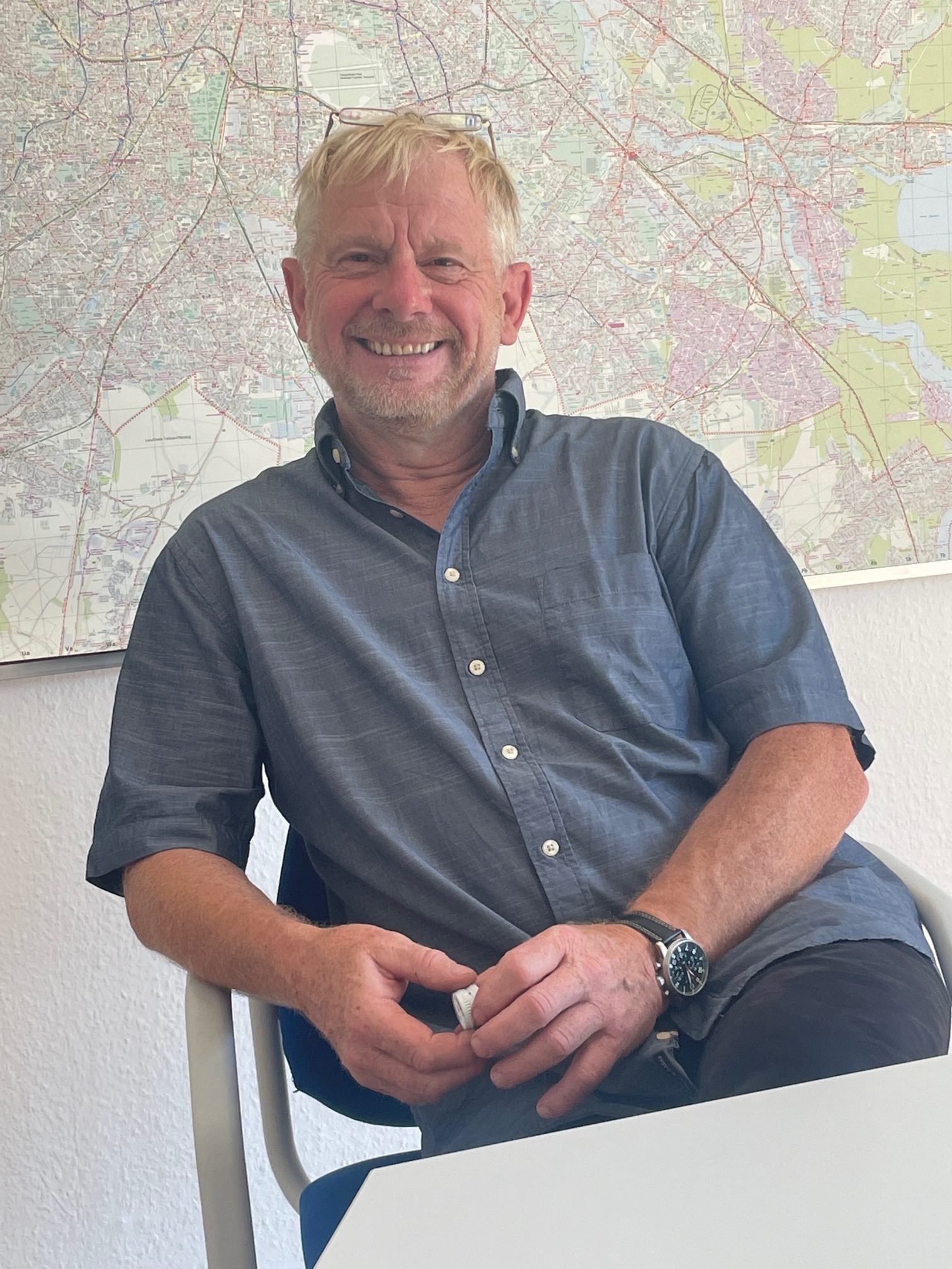 Olaf Kops, lächelnd vor einer Landkarte